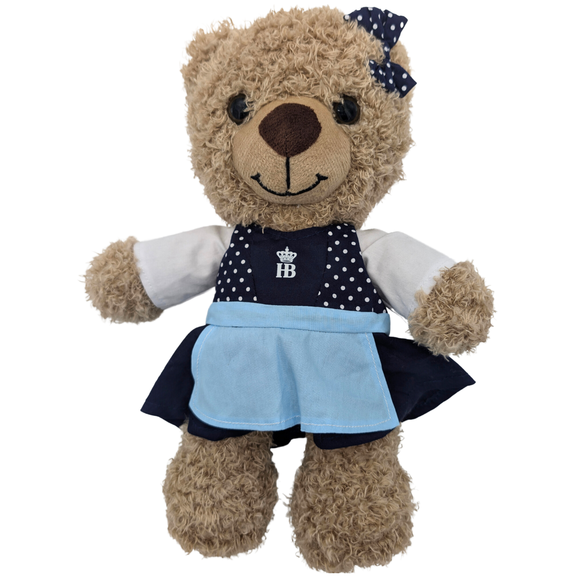 „Teddybär in einem Dirndl mit dunkelblauem Oberteil mit weißen Punkten, hellblauer Schürze und passender dunkelblauer Schleife mit weißen Punkten auf dem Kopf.“