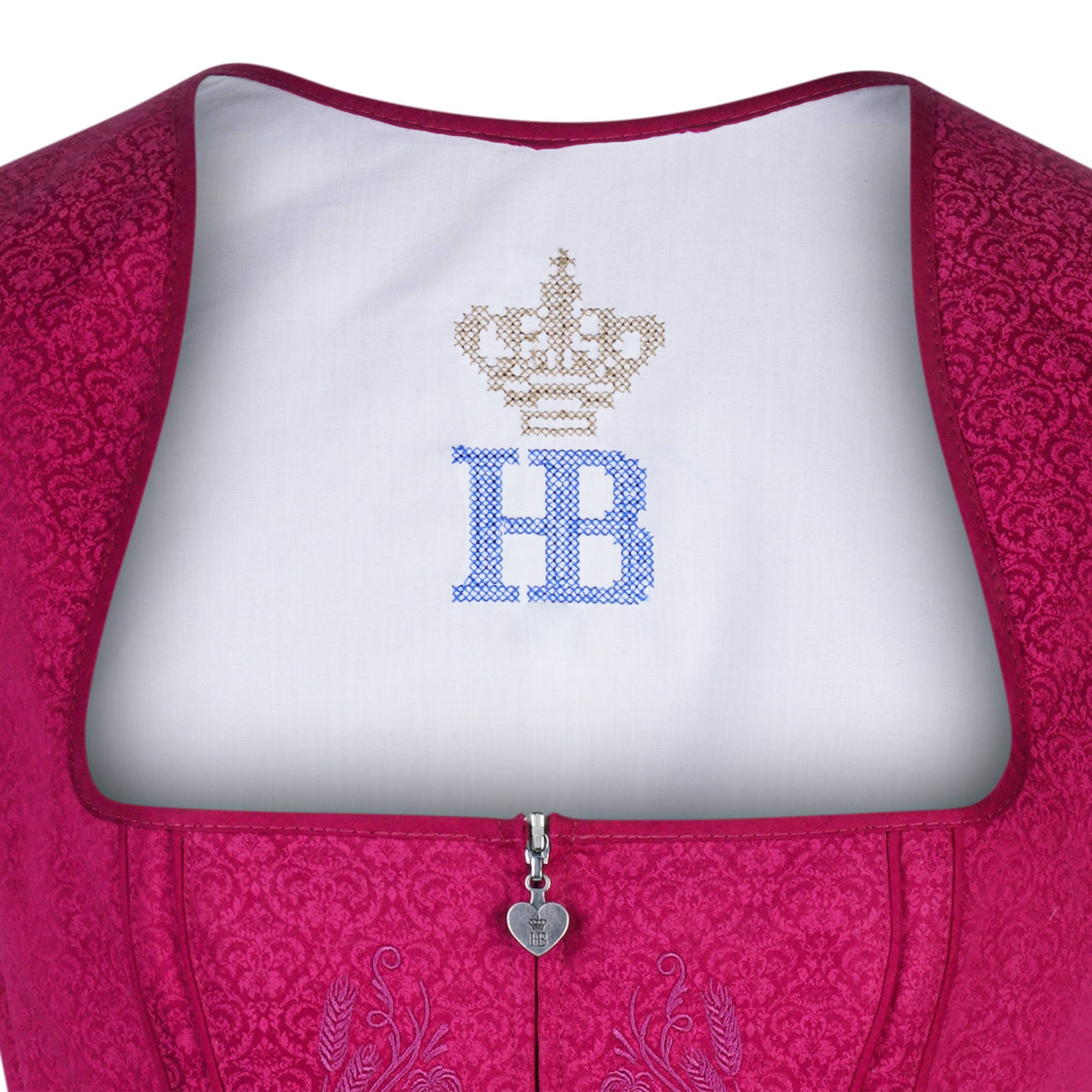 Nahaufnahme des pinken Dirndl-Mieders mit silbernem Herz-Zipper. Auf dem weißen Futterstoff ist oben das mit Glitzersteinen verzierte „HB“-Logo mit goldener Krone zu sehen.